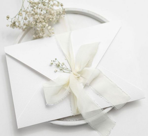 Biała koperta na zdjęcia 15x23 z&nbsp;szyfonową wstążką i&nbsp;gips&oacute;wką (papier fakturowany)