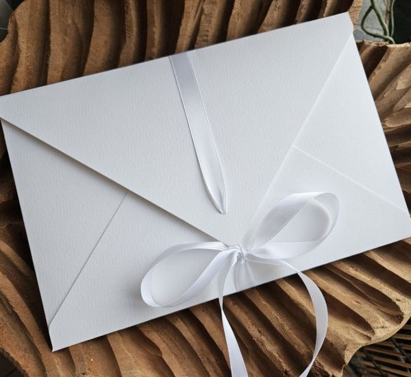 Biała koperta na zdjęcia 15x23 z&nbsp;wstążką (papier fakturowany)